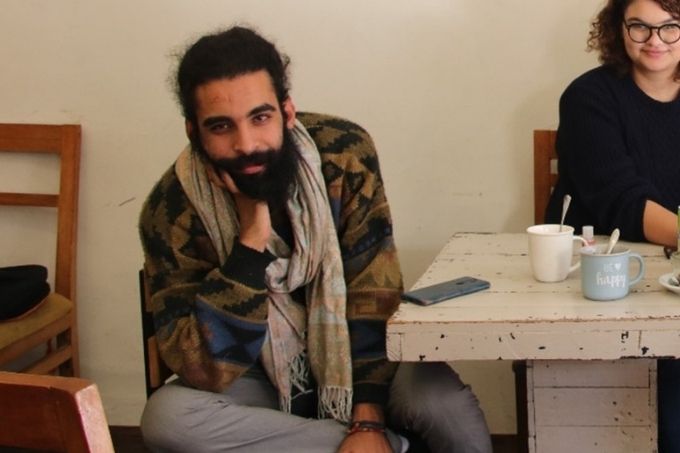 Ahmed Zarrouki på Café Liberté, under et af sine billeder fra den seneste demonstration.