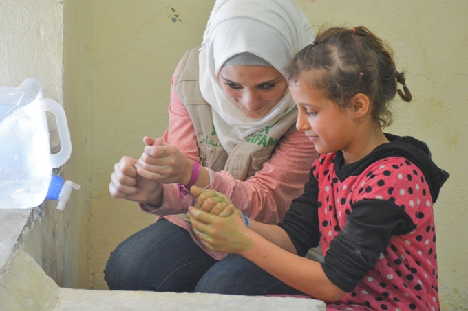 En Oxfam-ansat lærer syriske flygtningebørn om at vaske hænder - en af de mest effektive måder at forebygge sygdomme