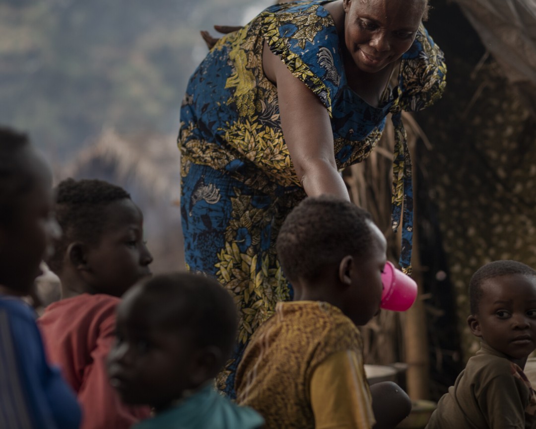 Leonie, 52-years-old, serves water to one of her grand-children in the Cesacoba site, near Bangassou, the Central African Republic, on March 3rd, 2021.