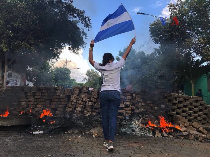 En kvindelig demonstrant nær en brændende barrikade. Det er Nicaraguas unge, der leder an i protesterne 